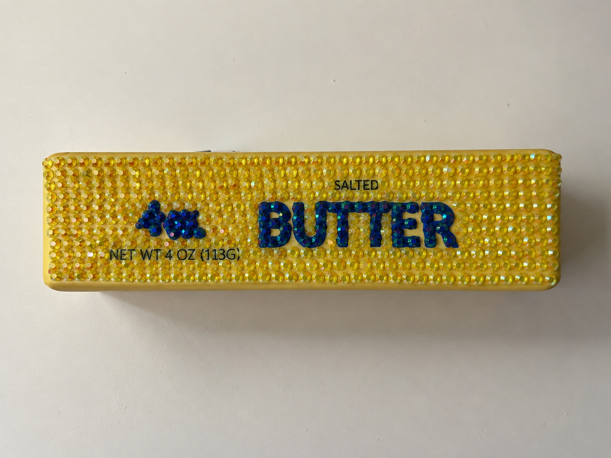 Butter squishy bedazzled with yellow rhinestones and blue stone BUTTER lettering